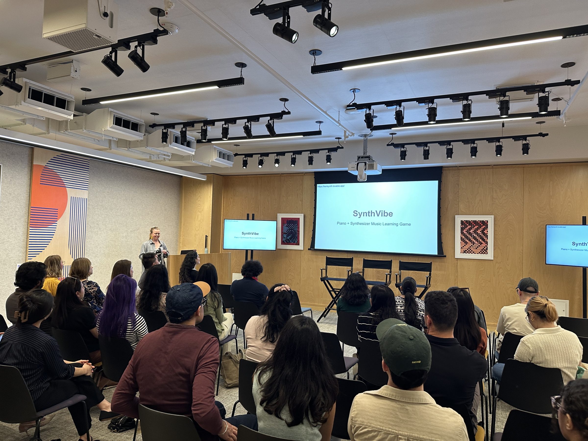 Keri Fullwood presenting SynthVibe — a piano and synthesizer music learning game built with Lovable — at the Huddle Design & AI event she organized and hosted